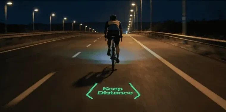 Cyclist riding at night with an IRIS Green road projection